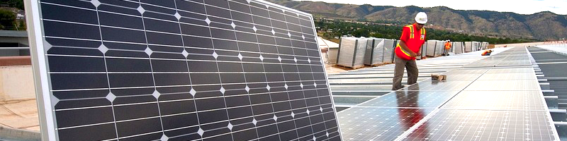 Solaranlagen Arbeiter bauen eine Photovoltaikanlage auf. Im Hintergrund sind Berge zu sehen.