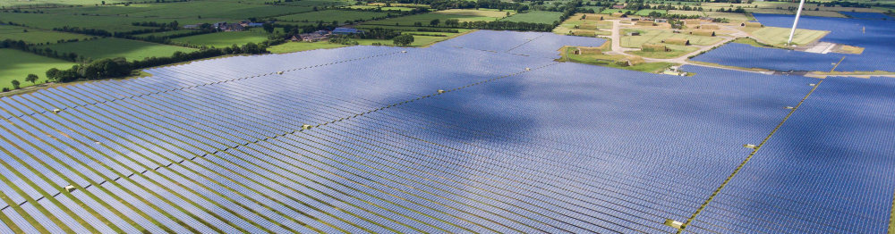 Großes Feld mit Photovoltaikanlage in mehreren Reihen als Panoramablick.