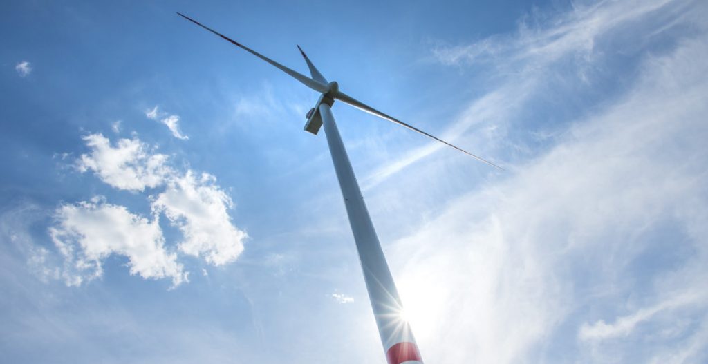 Windkraftanlage ragt in den Himmel, der mit Schleierwolken bedeckt ist.