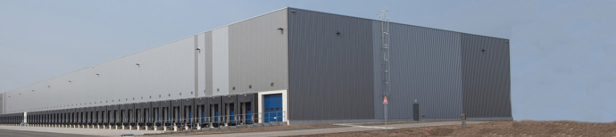 cb-spartners Logistikimmobile-schmal Große graue Logistikhalle mit blauen Toren.
